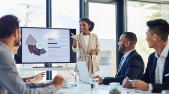 Business meeting, businesswoman and presentation on screen of tv in modern boardroom with colleagues. Workshop, speech and black woman or speaker speaking with coworkers in conference room